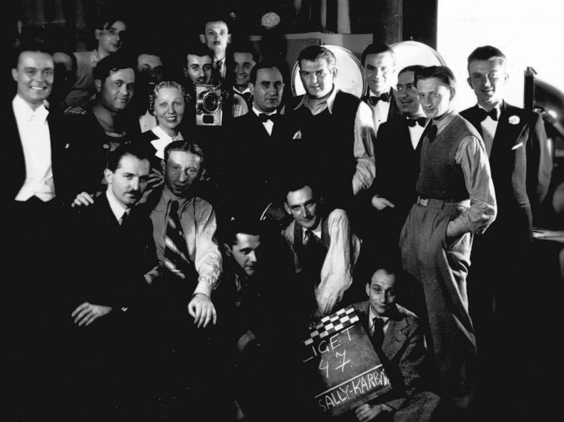 A Mindenki muzsikája című hangosfilm-sorozat egyik epizódjának forgatásakor készült stábfotó 1936-ból. A képen balról az első Weygand Tibor énekes, mellette jelmezben Fekete Pál tenorista, a kamera mögött (valószínűleg) Karbán József operatőr, a kame