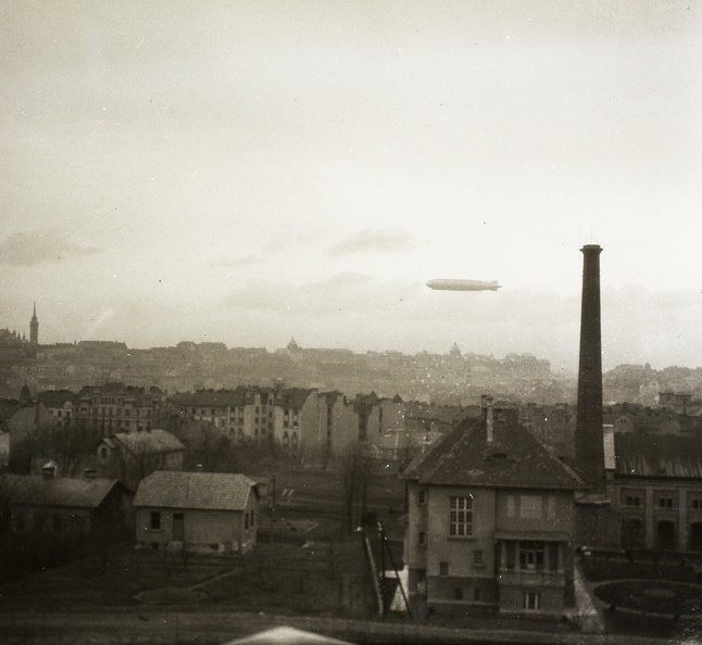 előtérben az Ügyész utca, jobbra a vízművek épülete az Istenhegyi útnál. A Kék Golyó utca és a Nagyenyed utcai házak hátterében a budai Vár és a Graf Zeppelin léghajó.
