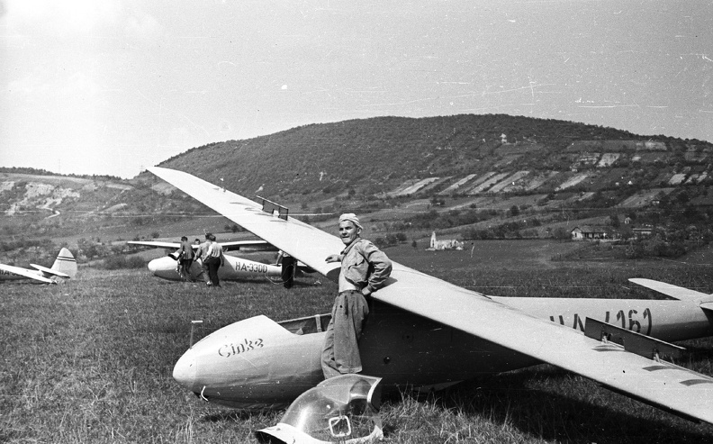 C-2 Cinke vitorlázó repülőgép, előtte Durucz Jenő (MALÉV-kapitány) oktató. Takarásban egy Rubik R 08 D-Pilis. Távolban a Csúcs-hegy, előtte a Gercsei (vagy Gercsényi) templomrom.